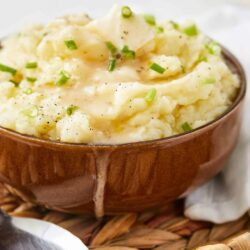 Creamy mashed potatoes with butter and chives in a rustic wooden bowl, perfect comfort food.