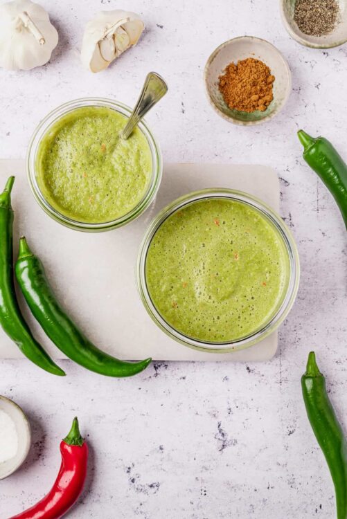 Green chili lime juice mixture in glass bowls with fresh jalapeños and spices.