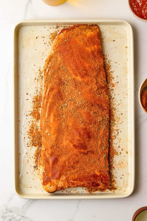 Juicy seasoned smoked brisket on a baking sheet ready to cook or serve. Classic BBQ smoked brisket with spices before roasting.