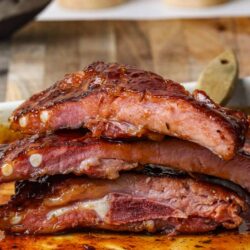 Juicy baked ribs glazed with barbecue sauce on a white dish. Perfect for summer barbecues and family dinners.
