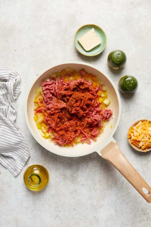 Minced beef and chopped potatoes cooking in a skillet for a savory beef hash.