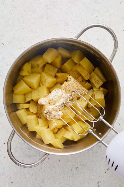 Creamy potato mixture with whipped cream and spices in a stainless steel bowl for baking recipes.