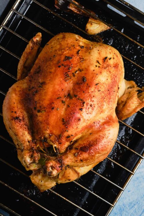 Roast chicken on baking rack with herbs and seasoning.
