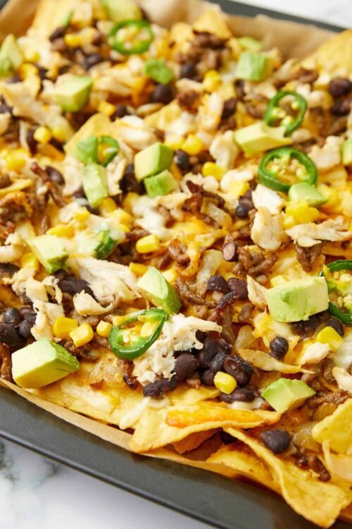 Savory nachos topped with black beans, chicken, corn, cheese, and avocado slices. Perfect for quick, flavorful snack or meal.