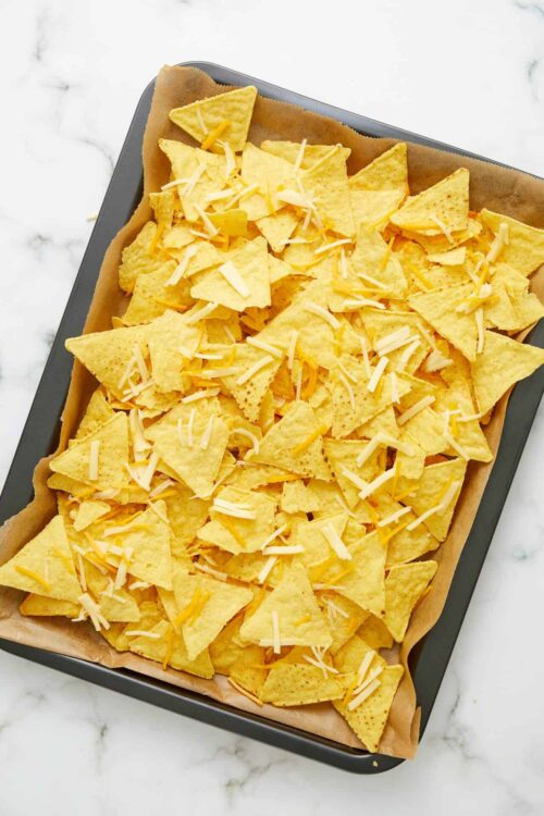 Golden cheesy baked tortilla chips on a baking sheet for snack or party recipes.