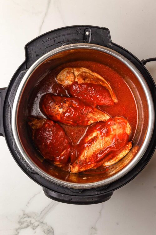Juicy chicken breasts cooking in a flavorful tomato sauce in an instant pot.