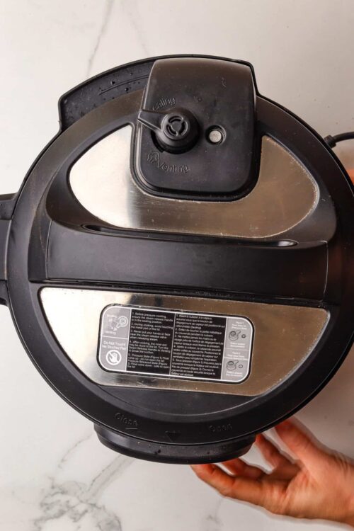 Pressure cooker lid with venting and sealing buttons for cooking and meal preparation.