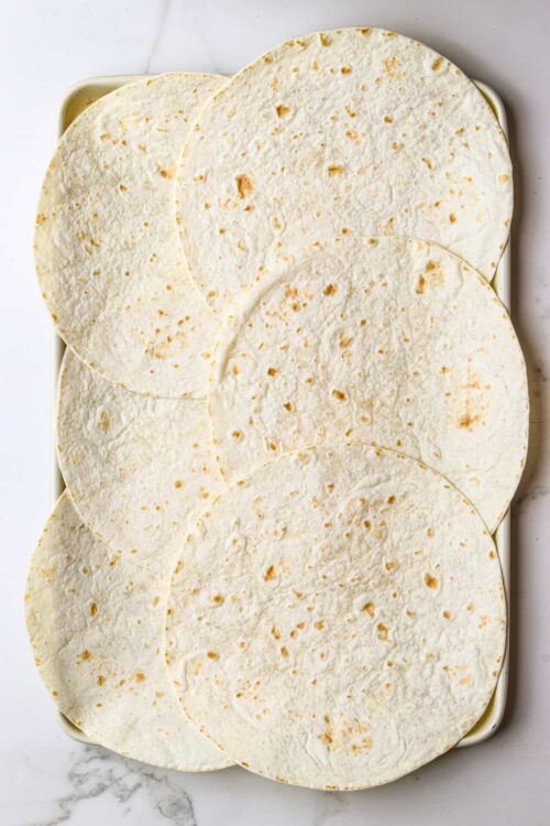 Delicious homemade flour tortillas stacked in a baking dish for authentic Mexican cuisine.