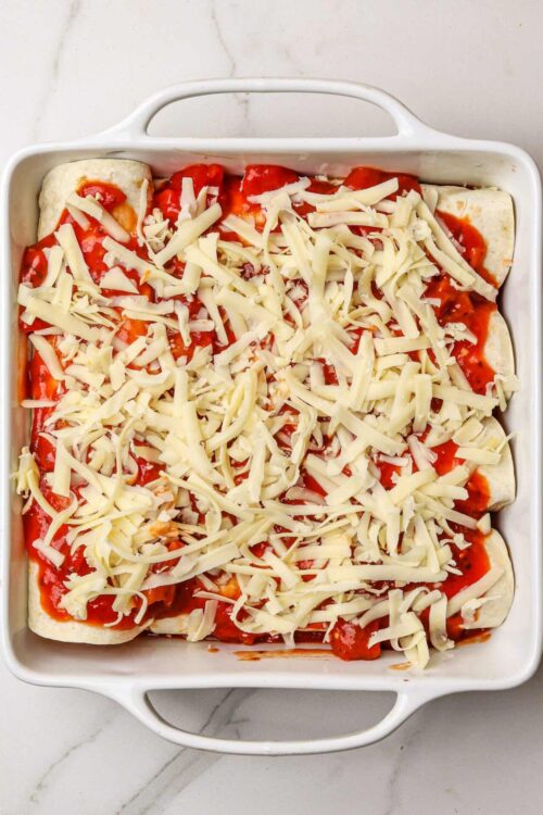 Cheese and marinara sauce pizza roll-ups in a baking dish.