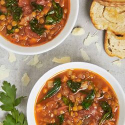 Comforting lentil and vegetable soup in white bowls with slices of toasted bread. Perfect for quick, healthy, and flavorful meals.