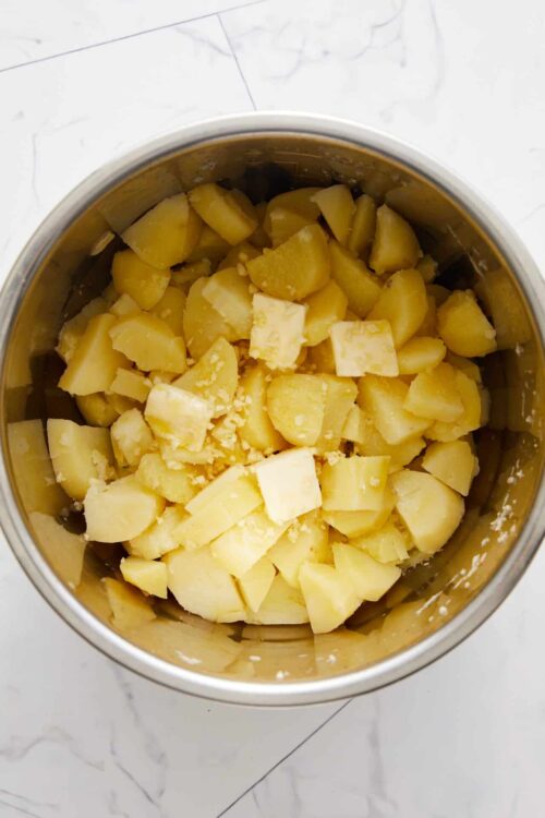 Buttered potato chunks in a stainless steel bowl.