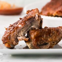 Juicy baked chicken drumsticks with crispy, golden skin on white plate.