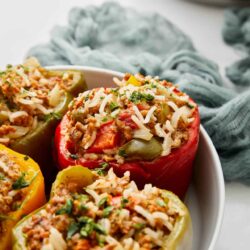 Stuffed bell peppers with ground meat, rice, and vegetables in a white bowl for healthy dinner or meal prep.
