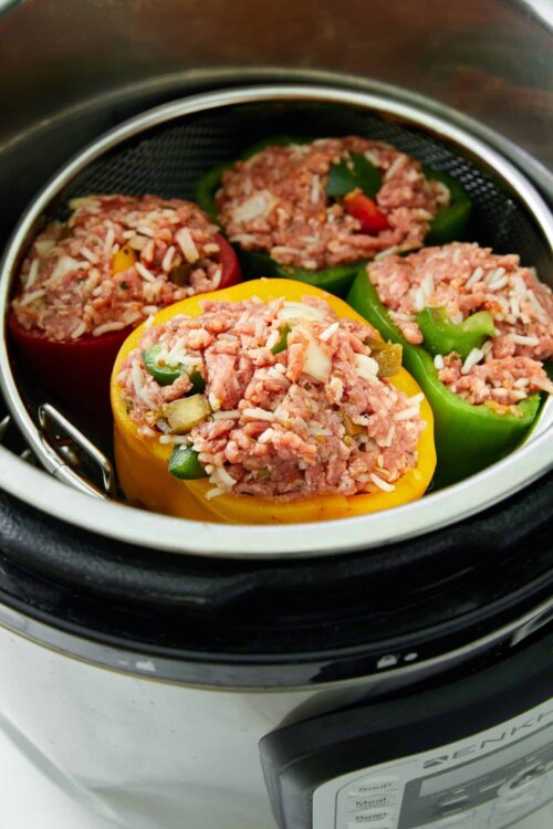 Colorful stuffed bell peppers in an air fryer, filled with seasoned ground meat and rice mixture, perfect for healthy, quick dinners.