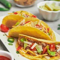Fresh homemade tacos with seasoned ground beef, fresh tomatoes, shredded cheese, and crisp lettuce on soft corn tortillas.