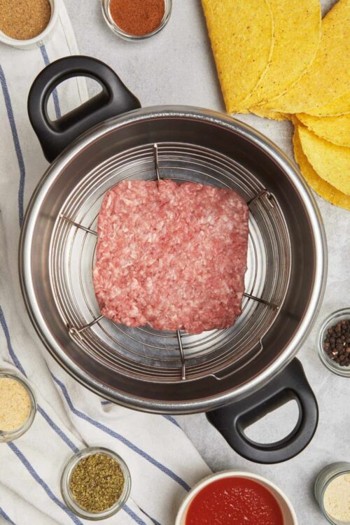 Ground beef inside a metal rack in a slow cooker, ready for cooking.