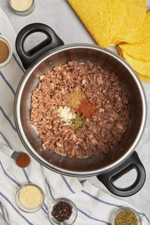 Ground beef with spices for tacos in a stainless steel pot.