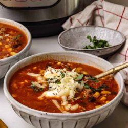 Hearty homemade chili in a rustic bowl topped with cheese and herbs, served with fresh garnishes. Perfect comfort food for cold days.
