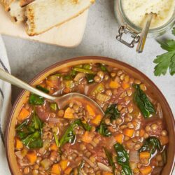 Creamy homemade butter in a glass jar with a spoon, alongside fresh baked bread slices.