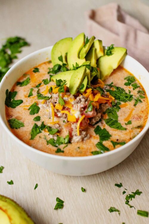 Creamy chipotle chicken soup garnished with fresh cilantro and sliced avocado. Ideal comfort food recipe from Baked Bree.