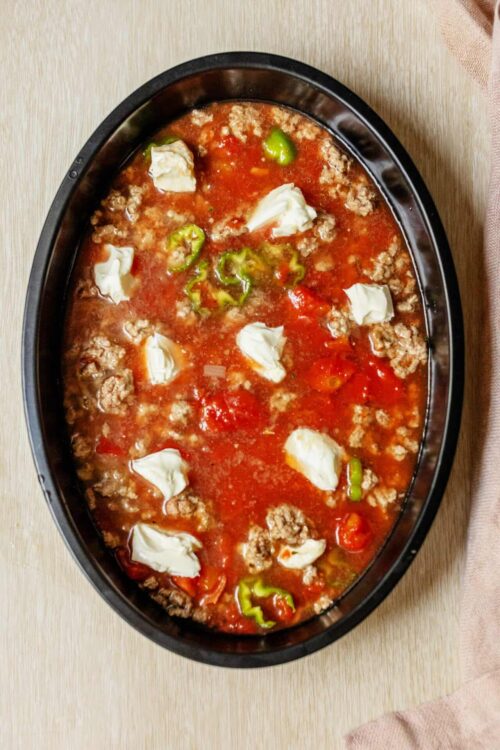 Savory meatball and green pepper soup in a black oval serving dish.