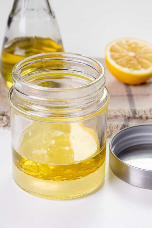 Drizzle bottle with lemon-infused olive oil on a white background.