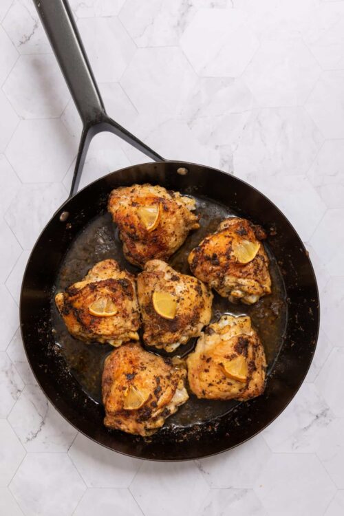 Juicy roasted chicken thighs in a skillet with lemon slices, crispy and flavorful, perfect for easy dinner recipes.