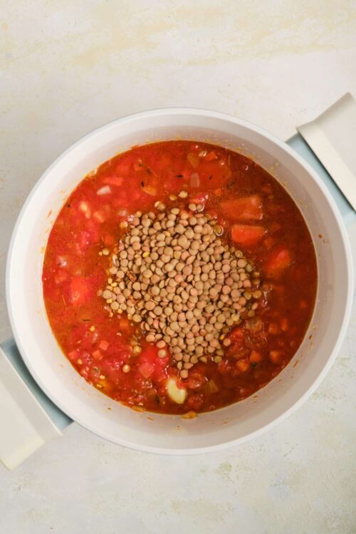 Cooked tomato lentil soup in a white slow cooker.