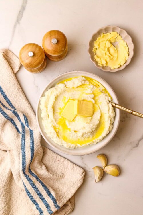 Butter, potatoes, mashed potatoes with butter in a bowl, cozy kitchen, classic comfort food, cooking ingredients, baked Bree recipe, creamy mashed potatoes, kitchen prep, home cooking, rustic kitchen setting.