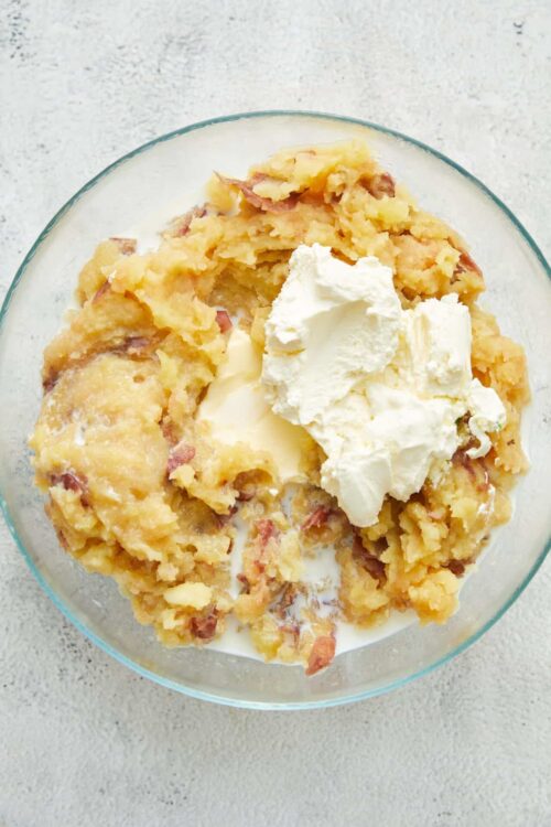Crispy potato casserole with bacon and sour cream in a glass bowl.
