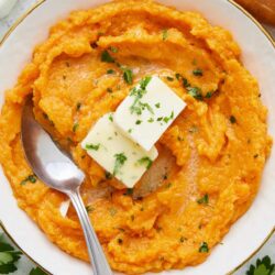 Creamy mashed sweet potatoes with butter and herbs, perfect for holiday dinners or cozy comfort food.