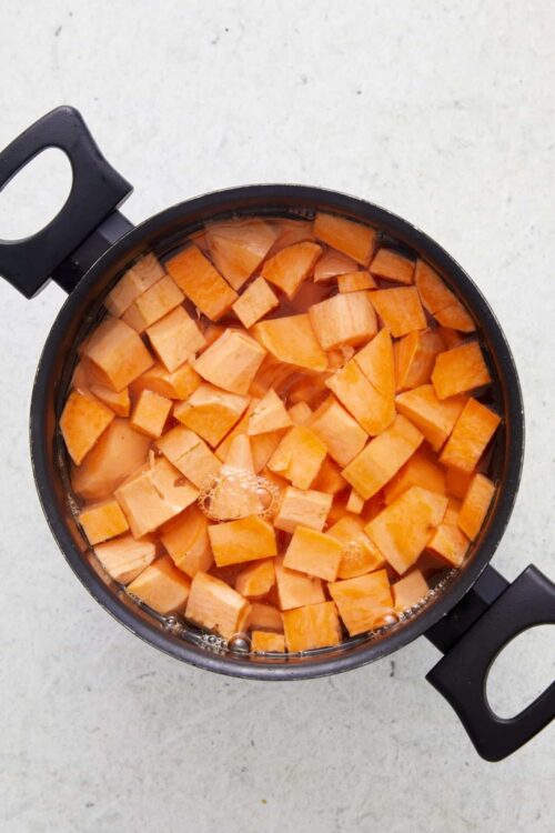 Sweet potato cubes cooking in a pot with water, ready for baking or mash.