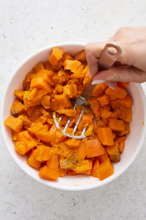 Sweet roasted butternut squash in a white bowl, prepared for baking or cooking.