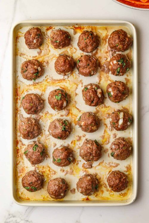 Savory baked meatballs with herbs in a creamy baking dish.