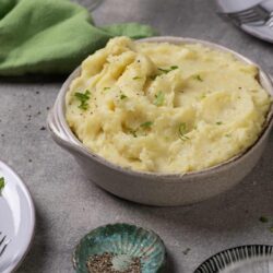 Creamy mashed potatoes with herbs in a rustic bowl.