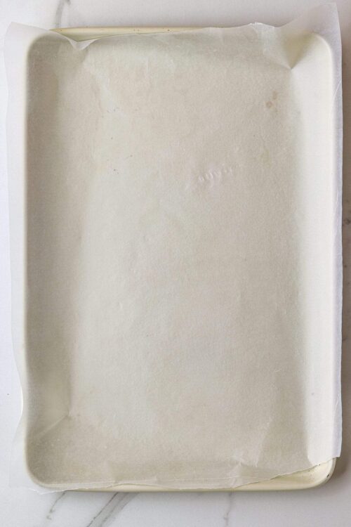 Raw lined baking sheet lined with parchment paper, ready for baking.