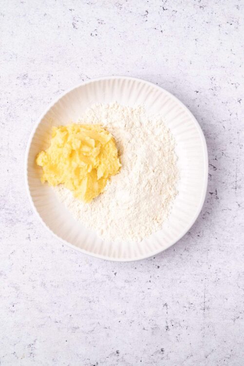 Flour, butter, and powdered sugar on a white plate for baking.