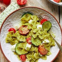 Fresh zucchini pasta with cherry tomatoes and mozzarella cheese on a rustic plate.