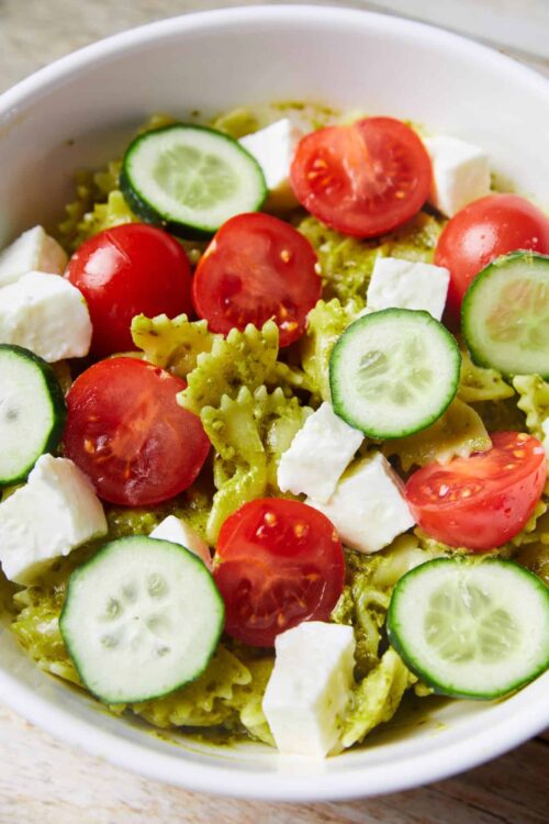 Fresh tomato, cucumber, and mozzarella pasta salad in white bowl.