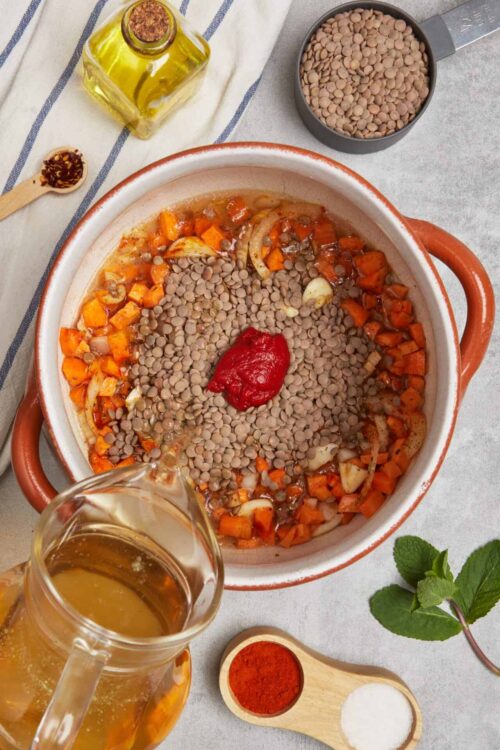 Minced lentil vegetable soup in a ceramic pot with tomato paste, carrots, onions, and spices.