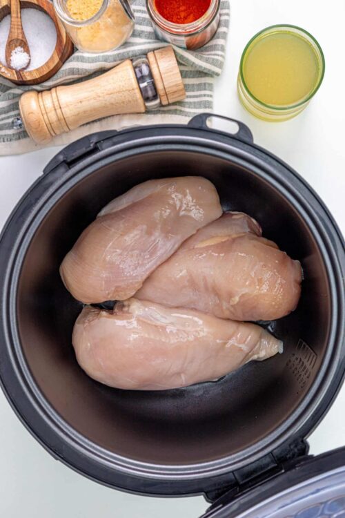 Raw chicken breasts in a slow cooker ready for cooking.