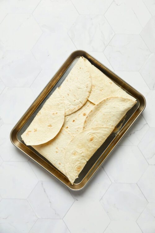 Freshly baked flour tortillas on a baking sheet.
