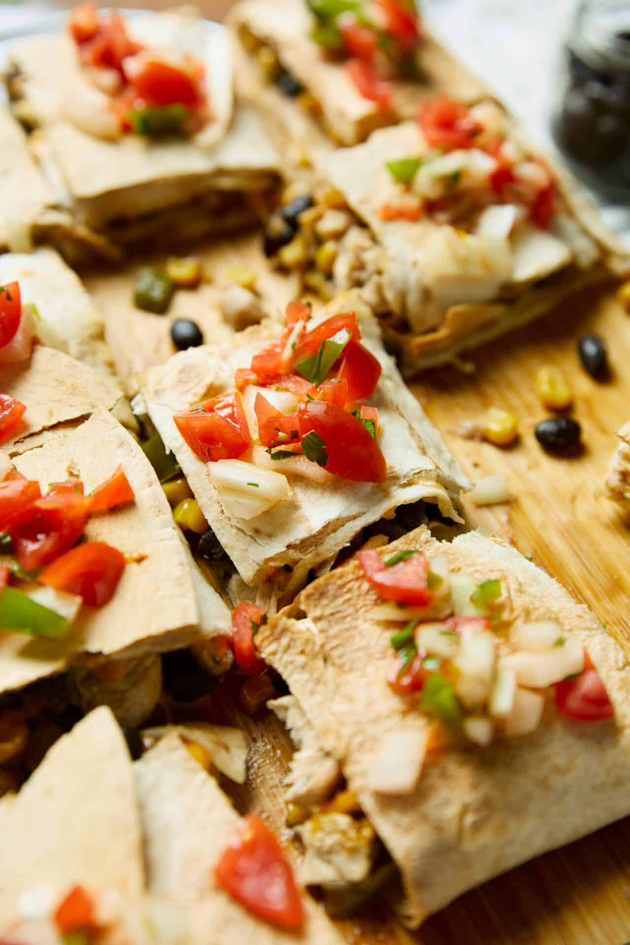 Cheesy chicken sour cream tacos with fresh tomato and green onion toppings on a wooden surface.