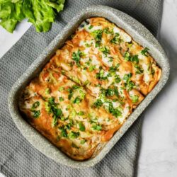 Baked cheesy enchiladas with fresh herbs in a baking dish.