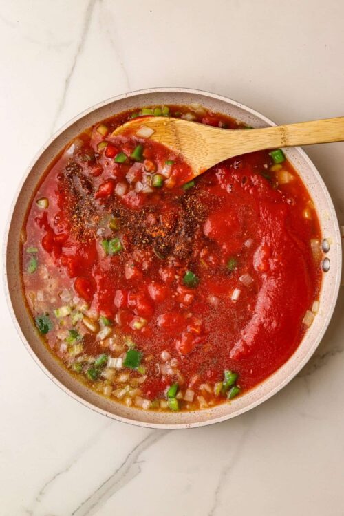 Savory homemade tomato soup with fresh herbs and vegetables in a white bowl.