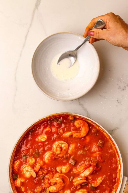 Creamy sauce mixture in a bowl with a hand stirring, ready for cooking or baking.