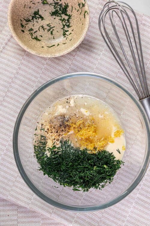 Fresh herb and lemon mixture in glass bowl with small herb bowl and hand mixer, perfect for baking recipes.