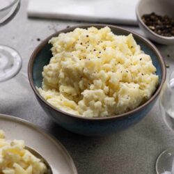 Creamy garlic mashed potatoes with black pepper in a blue bowl.