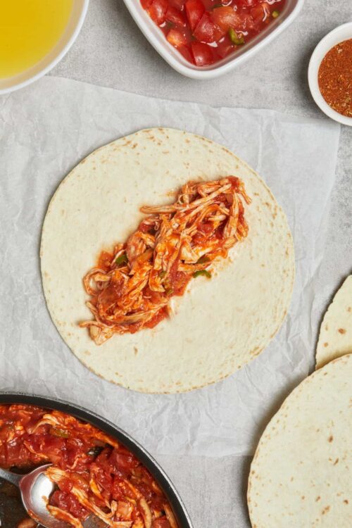 Shredded chicken filling in a soft flour tortilla for tacos.