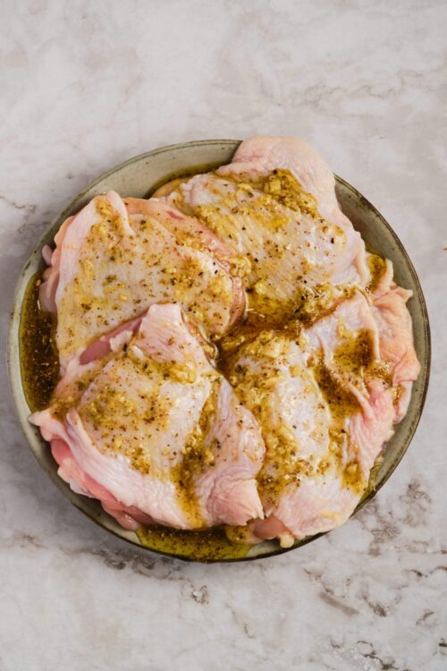 Succulent raw chicken thighs marinated with garlic and herbs ready for baking.